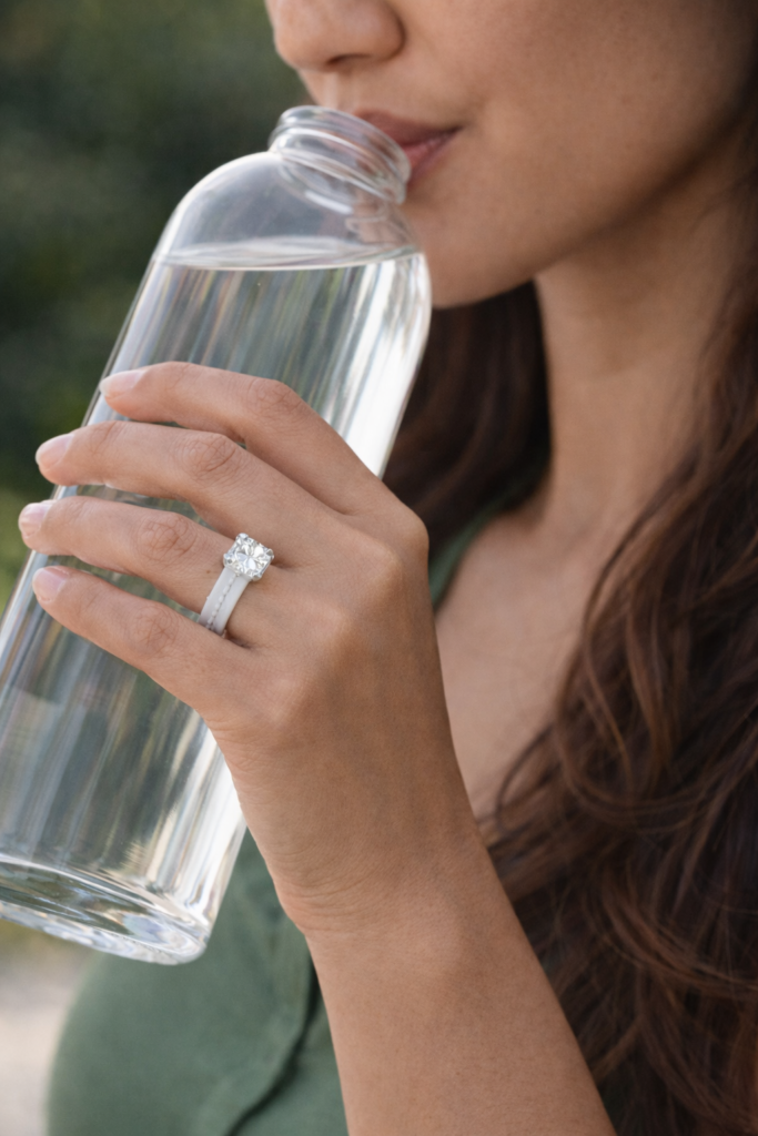 Woman wearing a silicone cubic zirconia engagement wedding ring while drinking from a glass water bottle outdoors